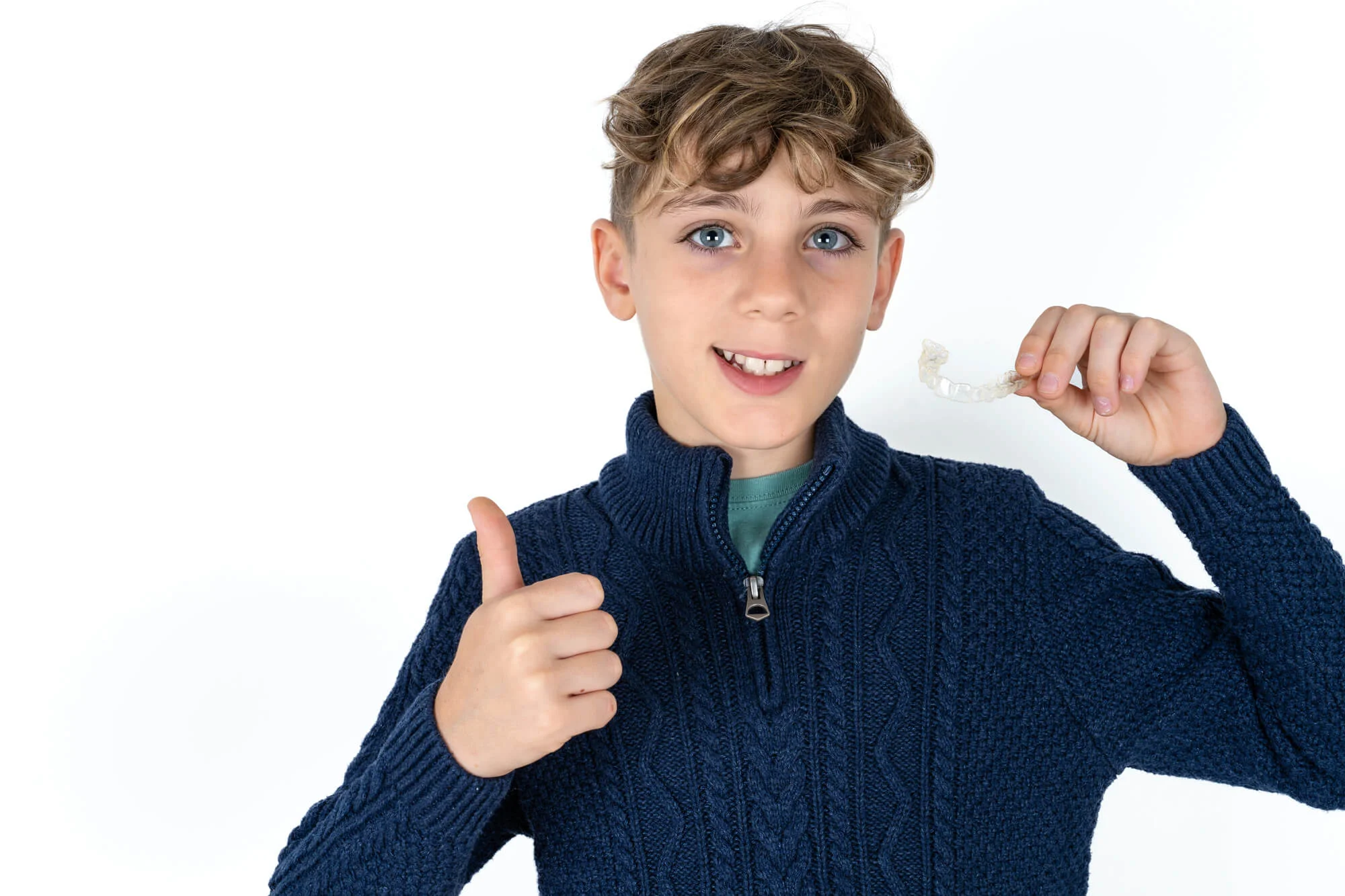 A-teen-boy-holding-a-clear-aligner-after-parents-complete-the-Invisalign-CareCredit-process