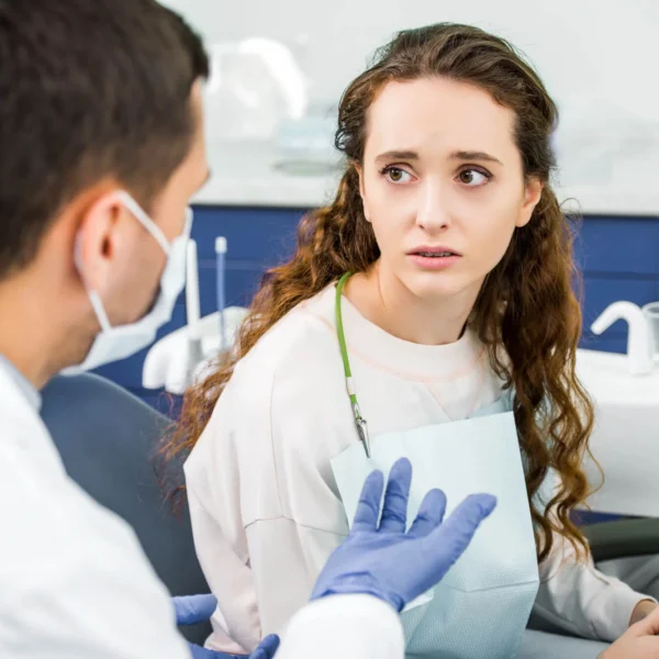 A worried-looking patient is looking at an emergency orthodontist in West Palm Beach