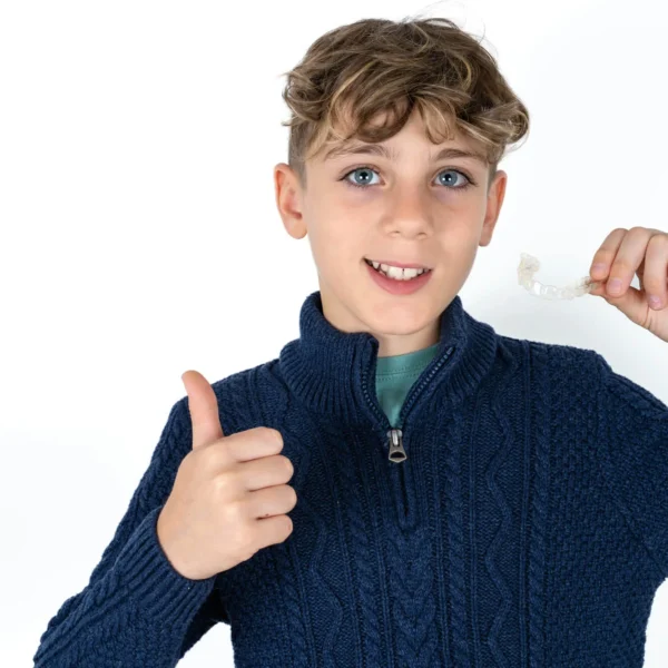 A young boy holding Invisalign when visiting orthodontist for teens.